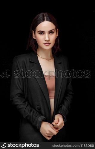 High fashion portrait of young elegant woman in black suit and beige top. Studio shot.