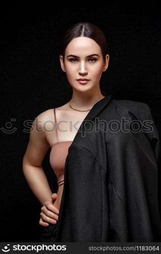High fashion portrait of young elegant woman in black suit and beige top. Studio shot. on a black isolated background