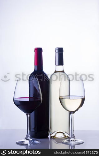 High glasses with red and white wine and two wine bottles. Glass of red wine