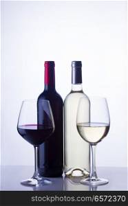 High glasses with red and white wine and two wine bottles. Glass of red wine