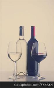 High glasses with red and white wine and two wine bottles, retro toned. Glass of red wine
