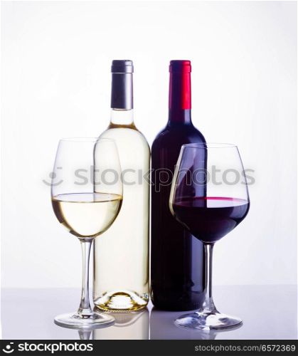 High glasses with red and white wine and two wine bottles toned image. Glass of red wine