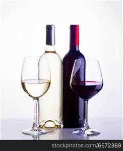 High glasses with red and white wine and two wine bottles toned image. Glass of red wine