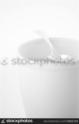 High key photo of a silver spoon lying on empty porcelain mug