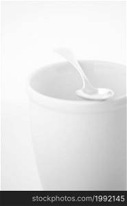 High key photo of a silver spoon lying on empty porcelain mug