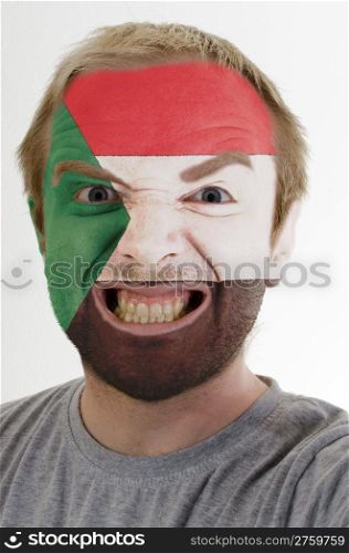 High key portrait of an angry man whose face is painted in colors of sudan flag