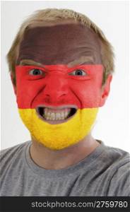 High key portrait of an angry man whose face is painted in colors of german flag