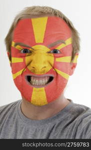 High key portrait of an angry man whose face is painted in colors of macedonia flag