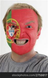 High key portrait of an angry man whose face is painted in colors of portugal flag