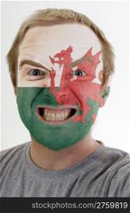 High key portrait of an angry man whose face is painted in colors of wales flag