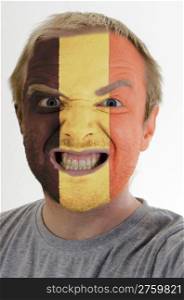 High key portrait of an angry man whose face is painted in colors of belgium flag