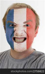 High key portrait of an angry man whose face is painted in colors of france flag