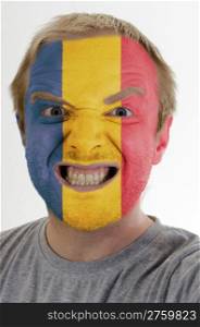 High key portrait of an angry man whose face is painted in colors of romania flag