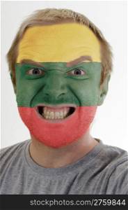 High key portrait of an angry man whose face is painted in colors of lithuania flag