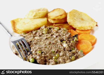 High key shot of minced beef cooked with onion, garlic, peas and herbs, served with sautee potatoes and boiled carrots. This is a simple, slightly old-fashioned British-style meal,