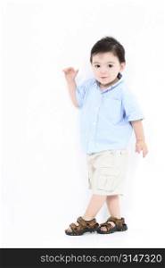 High Key Toddler Boy Standing Against White Wall in summer clothes. Not Isolated.