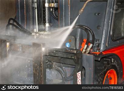 High pressure water jet hosing down the front side of a forklift