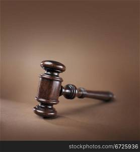 High quality mahogany wooden gavel on brown background. Very short depth-of-field.