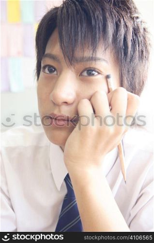 High school boy resting his cheek on his hand