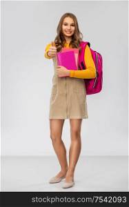 high school, education and people concept - smiling teenage student girl with backpack and books over grey background. teenage student girl with backpack and books