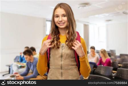 high school, education and people concept - smiling teenage student girl with backpack over lecture hall background. happy teenage student girl with backpack at school
