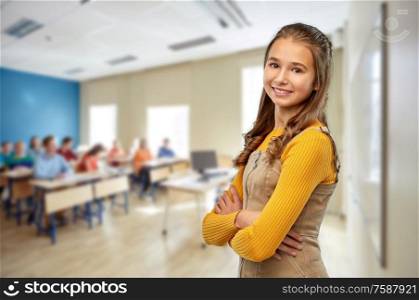 high school, education and people concept - smiling young teenage student girl with crossed arms over classroom background. smiling student girl with crossed arms at school