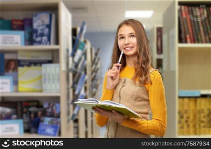 high school, education and vision concept - happy smiling teenage student girl with book and pen over library background. smiling student girl with book and pen at library