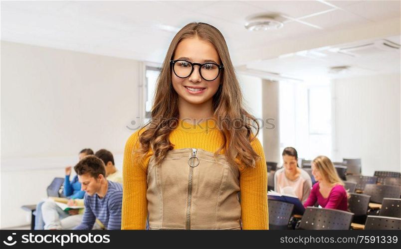 high school, education and vision concept - smiling teenage student girl in glasses over lecture hall background. smiling teenage student girl in glasses at school