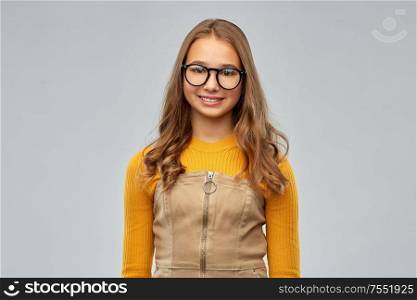 high school, education and vision concept - smiling teenage student girl in glasses over grey background. smiling teenage student girl in glasses