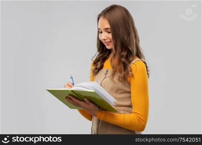 high school, education and vision concept - smiling teenage student girl with notebook or diary over grey background. teenage student girl with notebook or diary