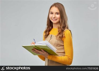 high school, education and vision concept - smiling teenage student girl with notebook or diary over grey background. teenage student girl with notebook or diary