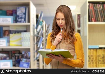 high school, education and vision concept - teenage student girl with book and pen over library background. student girl with book and pen at library