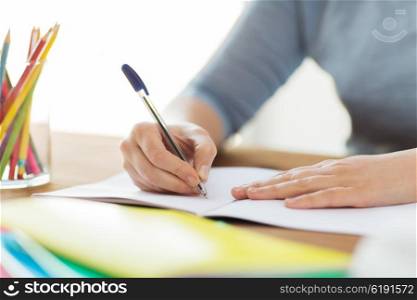high school, education, people and learning concept - close up of student or woman writing to notebook at home