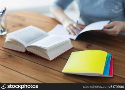 high school, education, people and learning concept - close up of young student or woman with book and notebooks at home