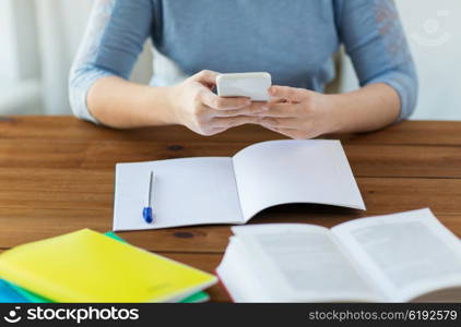 high school, education, people and learning concept - close up of young student or woman with smartphone, book and notebook at home