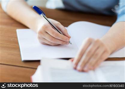 high school, education, people and learning concept - close up of young student or woman with book writing to notebook at home
