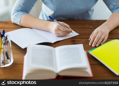 high school, education, people and learning concept - close up of young student or woman with book writing to notebook at home