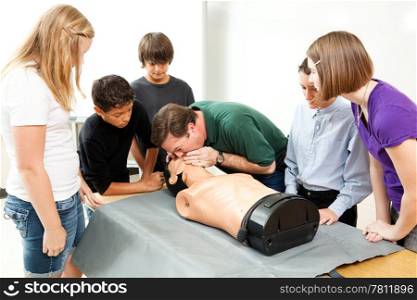 High school health class instructor demonstrates CPR lifesaving techniques for his students.
