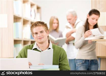 High school library - happy student with book and laptop