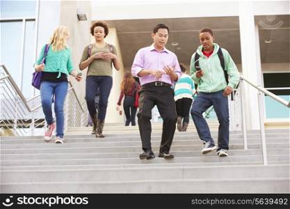 High School Pupils And Teacher On Steps Outside Building