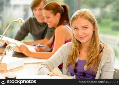 High-school student taking notes in study room smiling education campus