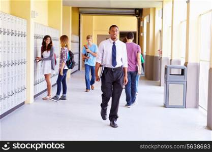 High School Students And Teacher Walking Along Hallway
