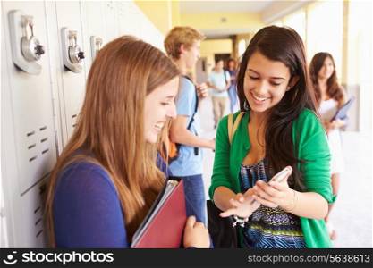 High School Students By Lockers Looking At Mobile Phone