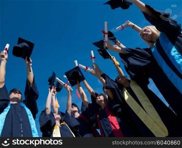 high school students graduates tossing up hats over blue sky.