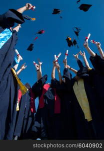 high school students graduates tossing up hats over blue sky.