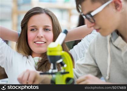High School students. Group of excited students working in class with microscope discovering how cells looks like