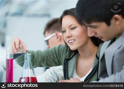 High School students. Group of students working at chemistry class: mixing reagent liquids and using glassware