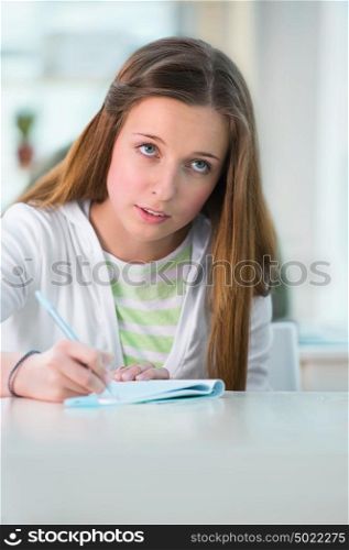 High School students. Pretty female student making notes in classroom during lecture
