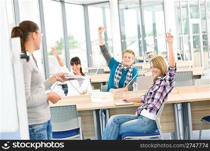 High school students raising hands, in classroom with professor