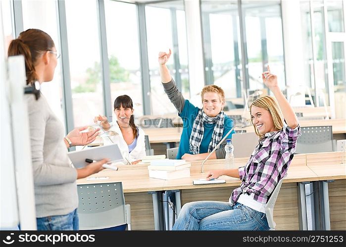 High school students raising hands, in classroom with professor